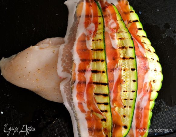 Теперь кладем перед собой одну половинку грудки и накрываем ее сверху внахлест полосками бекона и кабачка, чередуя между собой.   