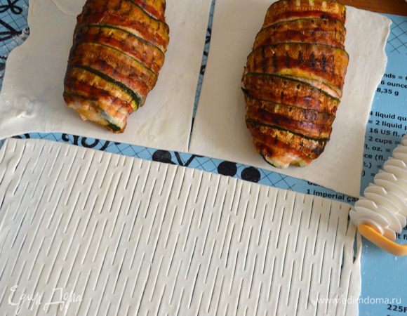 Духовку разогреть до 200 С. Слоеное тесто раскатать в тонкий пласт прямоугольной формы. Отрезать 1/3 полоски теста, разрезать пополам, у нас получится 2 прямоугольника. Положить на них уже остывшие грудки. Оставшееся тесто надрезать, используя специальный нож, или сделать надрезы обыкновенным ножом...   