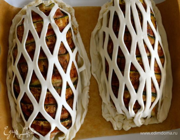 Надрезанное таким образом тесто разрезать на двое. Слегка взбитым яйцом смазать края теста, на котором лежат грудки, накрыть сверху сеточкой и как следует закрепить края. Обе грудки положить в форму для выпечки на пекарскую бумагу. 
