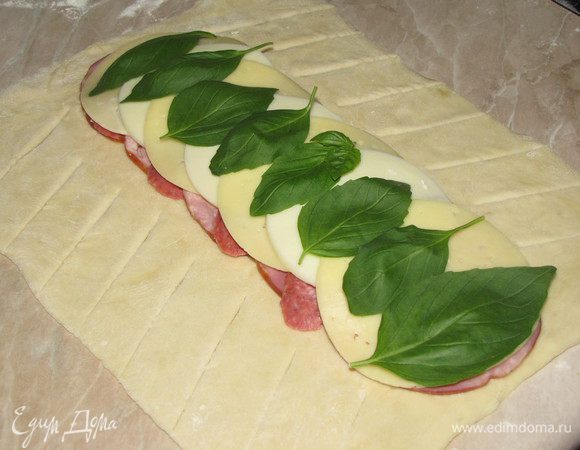 Снова закрыть листиками базилика. По краям теста сделать боковые надрезы.