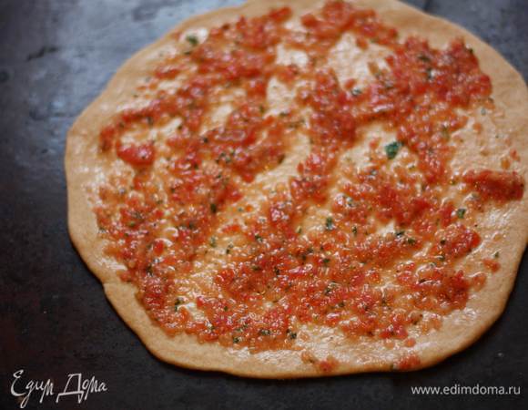 Раскатаем тесто в круг толщиной 0,5 см, намажем основу соусом и поставим в разогретую до 180 градусов духовку на 5-7 минут.