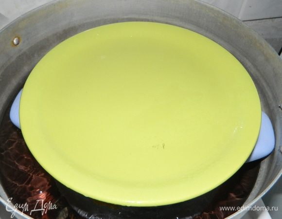 После того, как все овощи и мясо уложены, маленькую кастрюлю ставим в кастрюлю большего размера. Наливаем в большую кастрюлю воду. Вода должна доходить до ручек маленькой кастрюли. Накрываем маленькую кастрюлю тарелкой, чтобы внутрь не попадала кипящая жидкость или конденсат. 