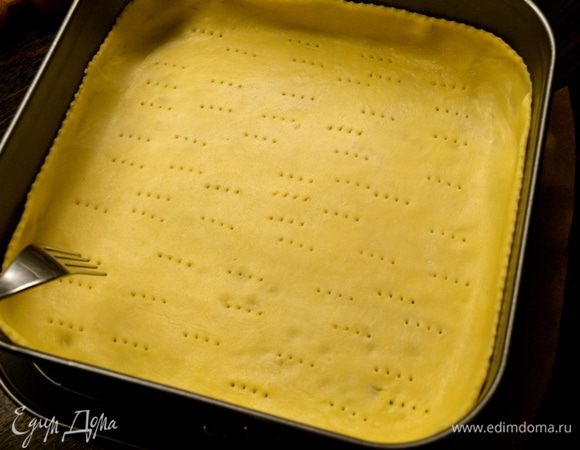 Духовку включить на 180 С. Подготовленную квадратную форму смазать маслом и присыпать мукой. (у меня со съемными бортами - очень удобная!) Песочное тесто достать из холодильника и раскатать. Выложить в форму, сформировать бортик и наколоть вилкой. 