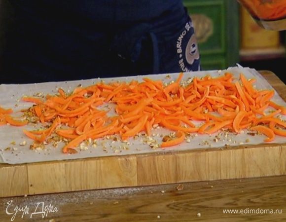 Посыпать тесто частью орехов со специями и равномерно разложить сверху натертую тыкву.