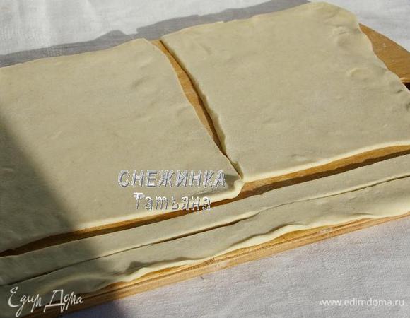 Слоёное тесто раскатываем в прямоугольник, не очень тонко (потом мы его будем ещё раскатывать). Отрезаем 2 полоски по всей длине, это будут «завязочки» мешочка, откладываем. Остальной пласт делим пополам.