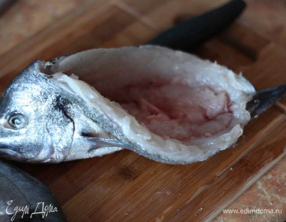 Должен получиться большой "карман", в который будет укладываться начинка. Рыбу хорошо промыть и обсушить тушки при помощи бумажных полотенец.Н атереть дорадо внутри и снаружи солью, свежемолотым перцем, майораном и сбрызнуть лимоном. Оставить на 15 минут.