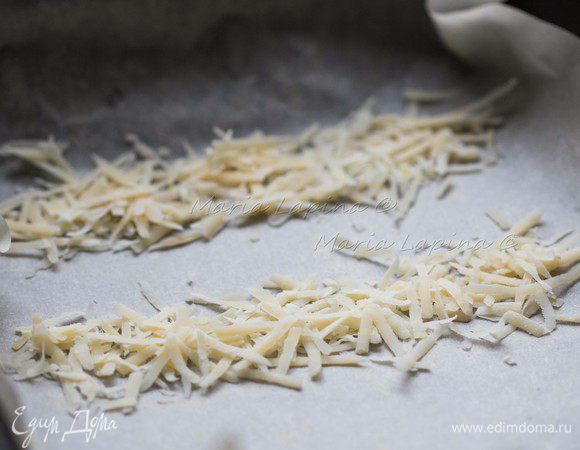 Чтобы приготовить сырные чипсы, разогрейте духовку до 200С, в форму или на противень выложите пекарскую бумагу или пергамент. Сыр натрите на средней или крупной терке, насыпьте полоски из сыра на противень. Ставим в духовку на 2-3 минуты, пока сыр не расплавиться. Достаем и даем пол минутки схватиться, затем аккуратно сворачиваем в красивые завитки. 