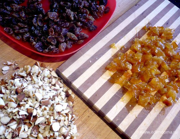 Приготовим начинку. Изюм замочим в кипятке на пару минут, затем сольем воду и обсушим его. Цукаты извлечем из варенья и нарежем кубиками. Орехи порубим. Яблоки очистим, удалим сердцевинку, нарежем дольками.