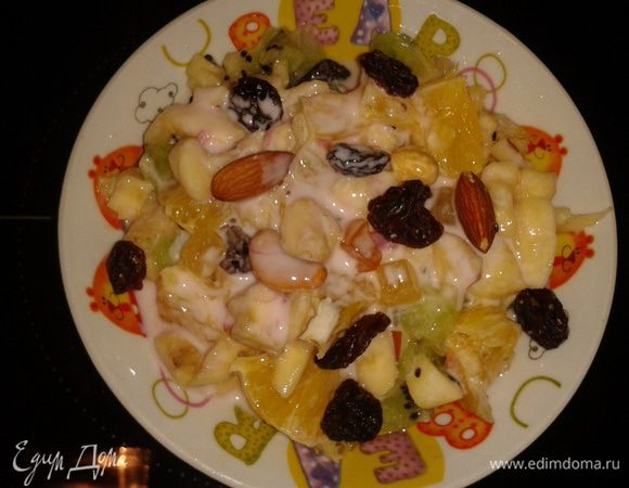 Детям можно подать десерт в тарелке, все фрукты перемешайте, добавьте йогурт, орешки и изюм.