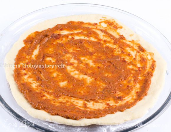 Трем на терке 1 помидор, разрезав его пополам. Таким образом шкурка останется у Вас в руке. Отправляем пюре в блендер, добавляем вяленые томаты, примерно 5 листиков базилика, оливковое масло, соль, перец и перебиваем в пюре. Смазать тесто томатным соусом равномерно. 