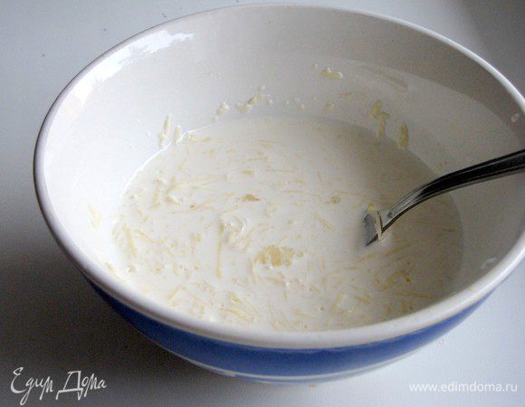 Тем временем приготовить соус. Натереть на мелкой терке сыр, выдавить через чеснокодавилку чеснок, смешать со сливками.
