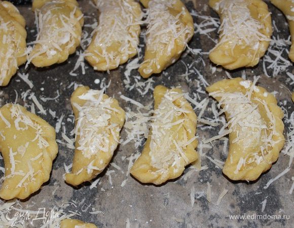 Выкладываем начинку в серединку каждого кружочка, защепляем края и выкладываем на противень, застеленный пекарской бумагой, смазываем молоком и посыпаем тертым сыром. Обрезки теста снова раскатать и вылепить еще пирожков, в итоге получилось 20 штучек