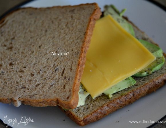 Хлеб можно обжарить на тостере предварительно. Выложить авокадо дольками, посолить и поперчить, затем сыр пластинками. Поставим в микроволновку на 30 секунд. 