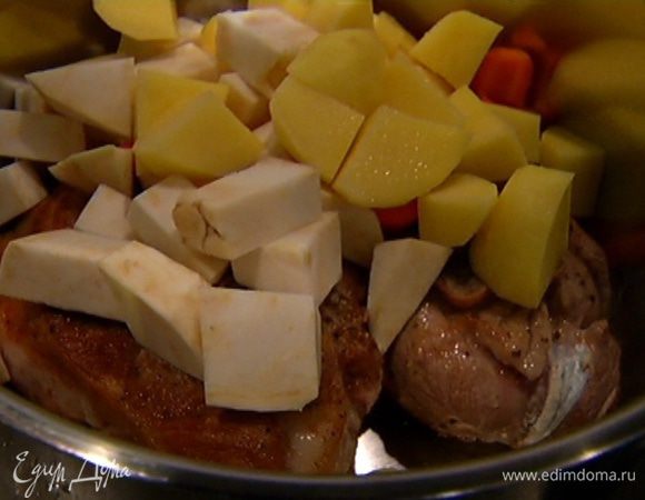 В кастрюлю с мясом выложить картофель, корень сельдерея, морковь и обжаренный лук с чесноком, поместить кастрюлю на сильный огонь, влить белое вино, перемешать и дать алкоголю выпариться.