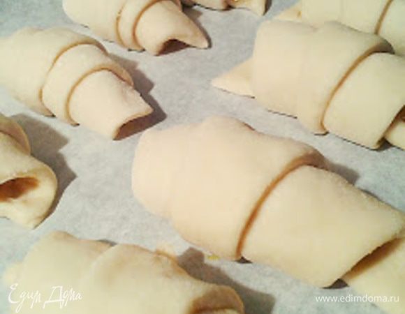 Закручиваем треугольники тугим рулетиком,начиная с широкого конца к узкому.Застилаем противень бумагой для выпечки и выкладываем круасаны. Оставляем на 10 минут.