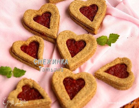 Готовые печенья снимаем с противня и даём полностью остыть. Целые сердечки смазываем небольшим количеством джема и сверху накрываем сердечками с вырезанным центром.