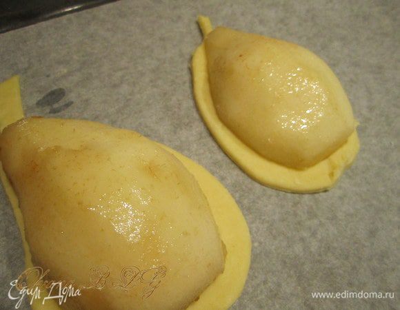 Тесто раскатать примерно 0,5 см толщиной. Вырезать по форме груш только больше на 1 см. В серединку груши положить творожной масы. Выложить половинки груш на тесто, края смазать яйцом.
