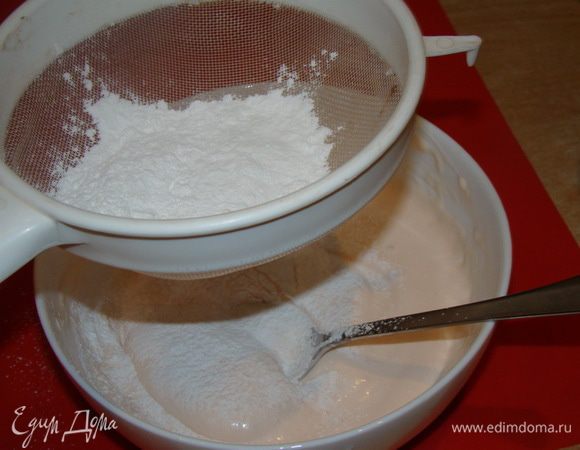 Размешивать ложкой, просеивая сахарную пудру.