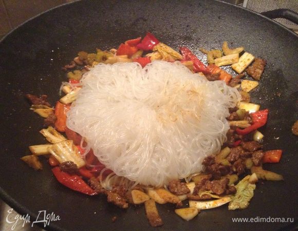 И в заключении добавляем рисовую лапшу. Обычно она очень длинная и я ее режу ножом прямо в сковороде, тогда ее легче будет перемешать, аккуратно все перемешиваем, чтобы наша лапша хорошенько впитала в себя все специи и соки овощей. 