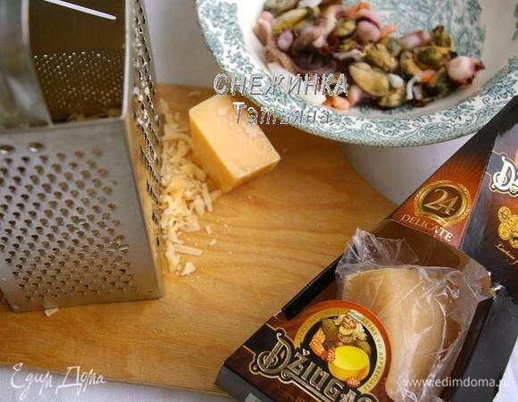 Для рулета пооловину сыра Джюгас натираем на крупной тёрке, вторую половину нарезаем тонкими пластинами. Морской коктейль опускаем в кипяток, даём снова воде закипеть и вынимаем.