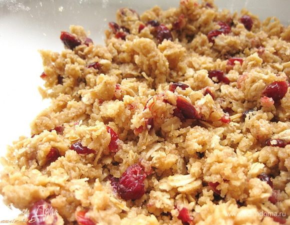 К овсяным хлопьям добавить муку, тростниковый сахар, соль и соду, погашенную лимонным соком, тщательно перемешать. Затем добавить клюкву и еще раз перемешать.