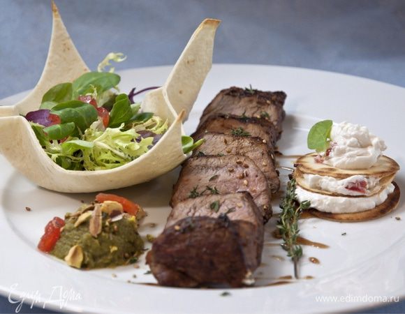 Выкладываем на блюдо, украшенное бальзамическим кремом, сначала обжаренные шайбочки, проложенные слоями из крема с козьим сыром. В подготовленные корзинки из лаваша выкладываем микс-салат с нарезанными помидорами, заправляем маслом, солью, и смесью измельченных перцев. 
Обжаренную вырезку нарезаем поперек волокон и распределяем на тарелке. 
Выкладываем мусс из кабачка украшаем фисташками и свежим тимьяном. 
