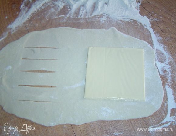 Каждый кусок теста раскатываем в тонкие прямоугольные пласты, на один край кладем сыр, а второй край надрезаем, как показано на фото.
