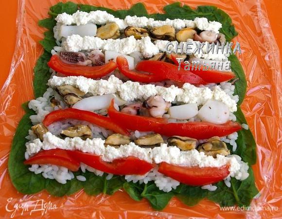 Морской коктейль опускаем в кипящую воду с добавлением молотого чёрного перца и лаврового листа. Держим пару минут. Помидор избавляем от сока и семян, мякоть нарезаем полосками. Если используете рикотту, посолите и поперчите её по вкусу. Теперь раскладываем на рисе рядами морской коктейль, помидоры и сыр.