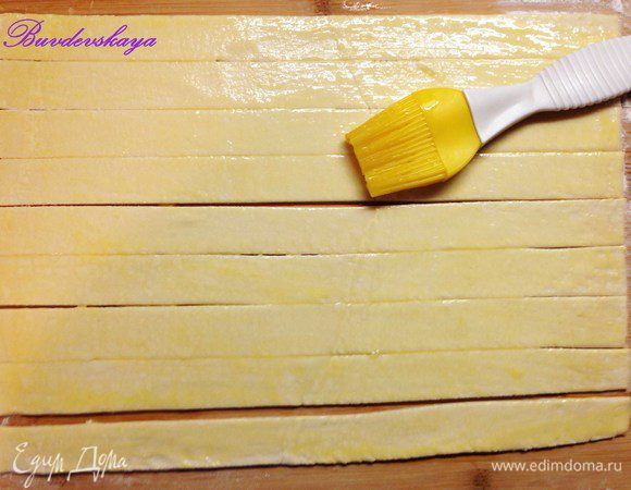 Раскатать тесто на присыпанной мукой поверхности и разрезать на полоски шириной 2,5- 3 см. Смазать полоски взбитым яйцом.