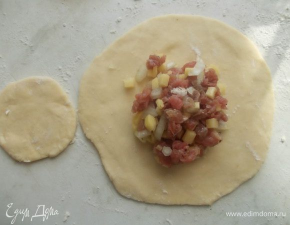 Тонко раскатайте тесто и выложите полную столовую ложку начинки на больший кусок теста. Накройте маленькой частью.
