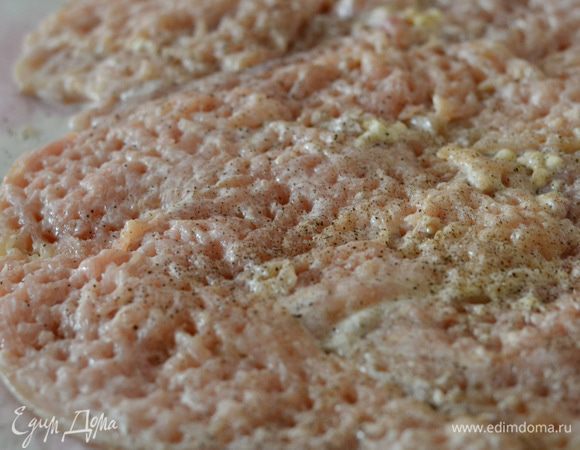 Выложить на пергамент или пищевую пленку кусочки отбитого филе в плотную к друг другу, чтобы краешки лежали друг на друге,еще раз отбить. Посолить, поперчить.