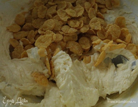 Кукурузные хлопья разделить пополам, часть измельчить. Добавить к творожной смеси сначала целые хлопья, перемешать и оставить на 10-15 минут.