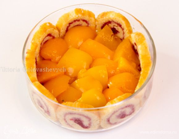 Растопите масло в сковороде. Положите персики, перемешайте и дайте подрумяниться. Сбрызните 2 ст. л. ликера. Готовьте, пока алкоголь не выпарится, фрукты размягчатся, но будут держать форму. Дайте остыть. Выложите сверху на кусочки рулета персики.