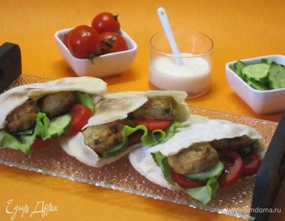 Для заправки смешать йогурт, измельченный зубчик чеснока, половину мелко нарезанной кинзы, лимонный сок и цедру. Приправить кайенским перцем и солью. Поставить в холодильник на 1 час.
У питы отрезать примерно треть, раскрыть, смазать изнутри оливковым маслом. Тонко нарезать помидоры, огурец, нарвать руками листья салата. Положить внутрь каждой питы по 2-3 фалафеля, огурец, помидор, салат, щедро полить йогуртовой заправкой и подать.