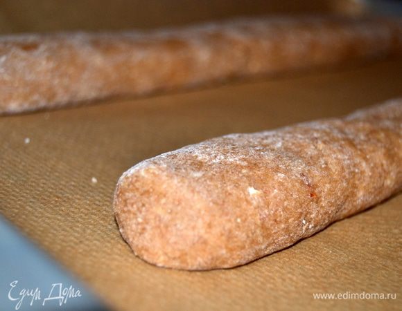 Получившееся тесто разделить пополам. Скрутить из каждой половинки два полена. Переложить заготовки на противень,застеленный бумагой.Тесто не должно соприкасается со стенками противня  и между собой, расстояние между заготовками лучше сделать побольше. Аккуратно прижать тесто ладошками, немного приплющив его.