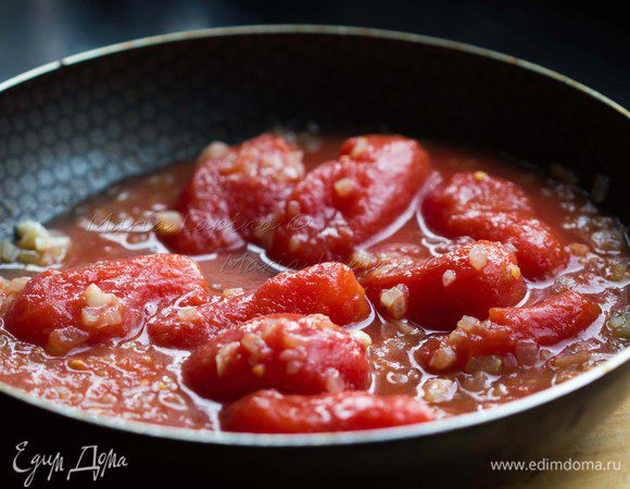 Добавить в сковороду томаты вместе с соком. Немного размять их лопаткой.