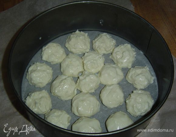 Дно формы (у меня 22,5 см в диаметре) выстилаем пергаментной бумагой. Из творожной массы мокрыми руками формируем шарики и кладем их на дно формы на небольшом расстоянии друг от друга,