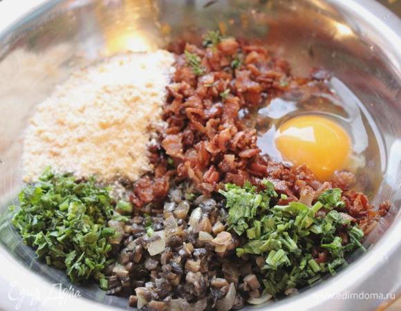 В миске смешать бекон, лук и грибы, панировочные сухари, яйцо, петрушку и тимьян. Посолить и поперчить начинку.