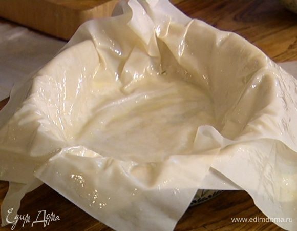 Смазать 4 листа теста фило оливковым маслом и уложить в керамическую форму для выпечки один на другой так, чтобы края теста свешивались из формы, в центр выложить начинку.