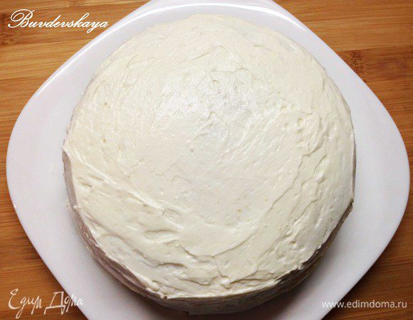 Вынимаем торт из холодильника, аккуратно вытаскиваем бумагу для выпечки из под низа. Наносим крем на верхнюю и боковые части торта.   