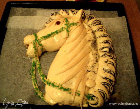 В оставшееся взбитое яйцо добавить сахарную пудру, еще раз взбить и смазать детали из пельменного теста. В процессе выпечки сахар карамелизируется и тесто останется светлым. Детали уздечки посыпать цветной кокосовой стружкой. Выпекать в духовке при температуре 180 градусов 40-45 минут. Если верх начнет слишком румяниться, накрыть фольгой.