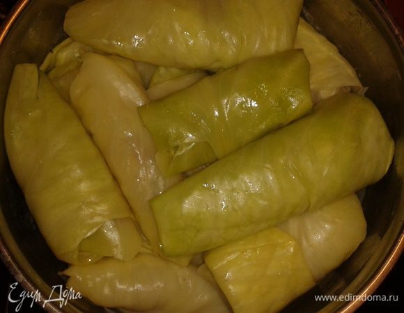 В капустный лист положить  начинку из фарша и риса, завернуть в трубочку и выложить в кастрюлю, где 1 слой - лук и морковь.