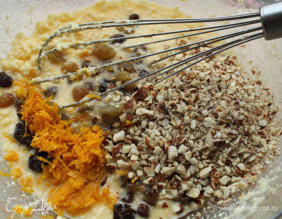 Добавить в тесто изюм, орехи и цедру апельсина, влить ванильную эссенцию.