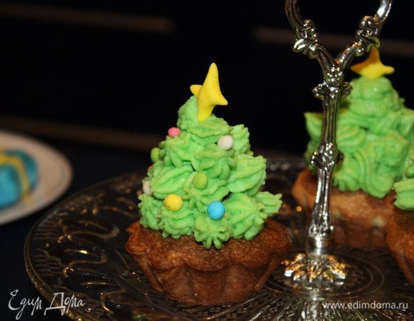 Возвращаемся к кексам. Аккуратно срезать верхушку. Нанести на срез крем и поставить конфету. 
При помощи кондитерского шприца/мешка делаем елочки.
