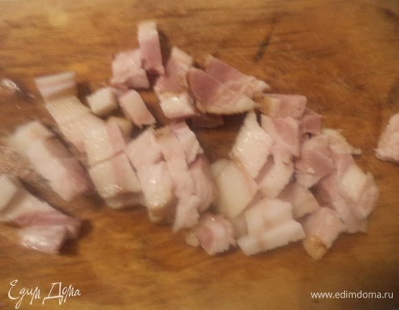 Луковицу очистить и порубить.
Бекон нарезать мелкими кубиками и нагревать в глубокой сковороде, пока из него не вытопится жир.