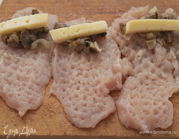 Куриные грудки вымыть, обсушить, посолить и приправить черным перцем.Отбить.Положить обжаренные шампиньоны с луком и кусочек сыра.