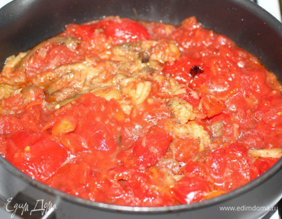 Вторую луковицу и оставшийся чеснок мелко порубить и пассировать на оливковом масле до мягкости. Добавить рубленные помидоры вместе с соком, очищенные и порезанные перцы и баклажаны. 