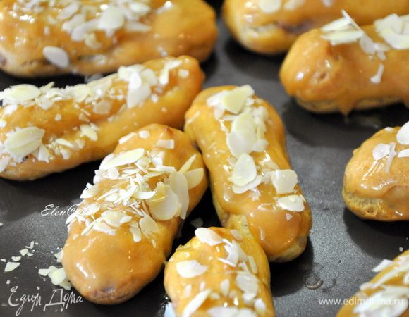 Теперь собираем наши эклеры.
Для этого с помощью кондитерского мешка начинить эклеры шоколадным кремом. И затем на каждый эклер нанести карамельный гляссаж. Я брала эклер за низ и окунала верхней стороной в гляссаж. Сверху пирожные посыпать миндальными лепестками.
