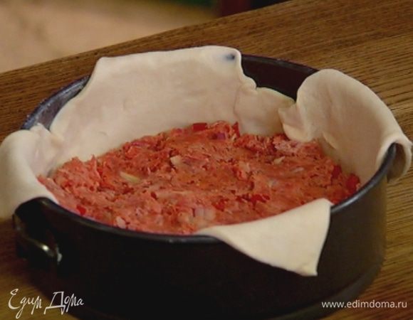 Разъемную форму для выпечки смазать сливочным маслом, уложить пласт теста так, чтобы углы немного свешивались из формы, и равномерно распределить начинку.