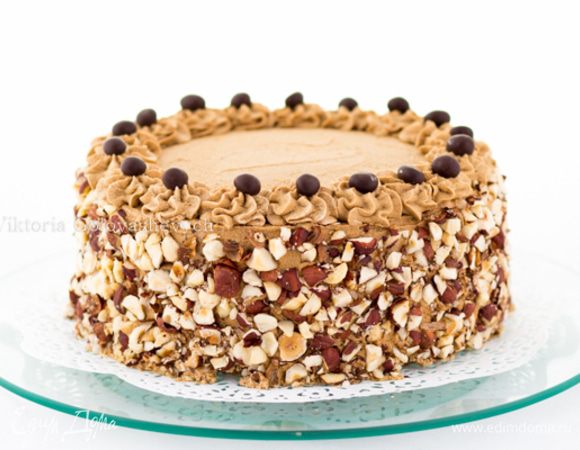 Обмазываем торт сверху и по бокам, разравниваем.
Из кондитерского мешка отсаживаем по краю торта "розочки-цветочки". 
Бока обсыпать подсушенным и крупно порубленным фундуком.
На каждую "розочку" положить по кофейному зернышку в шоколаде.
Дать настояться торту в холодильнике минимум 2 часа, лучше ночь.
